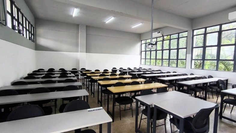 Salas de aula da nova unidade da Faculdade ITH, com ambiente moderno, amplo e iluminado, equipadas com projetor multimídia e mobiliário ergonômico para uma experiência de aprendizado aprimorada.