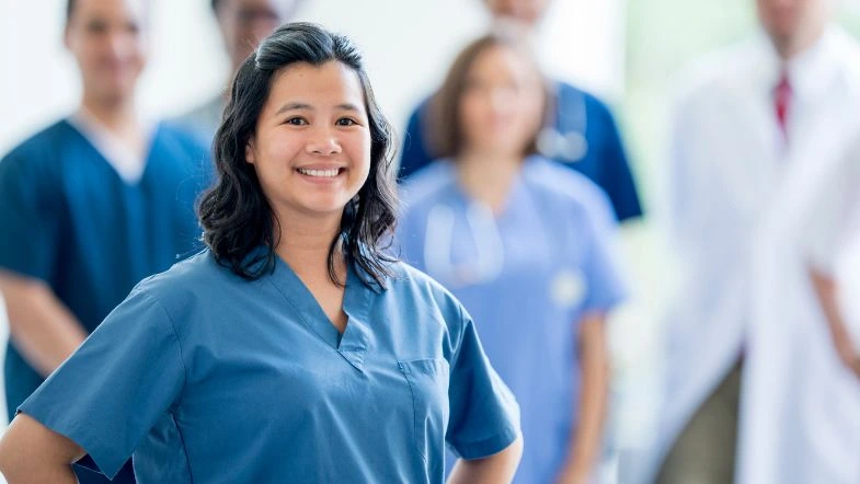 Enfermagem Obstétrica: o enfermeiro e a humanização do parto 9 Enfermeira obstetra sorridente em primeiro plano com equipe multiprofissional ao fundo, simbolizando liderança e confiança.