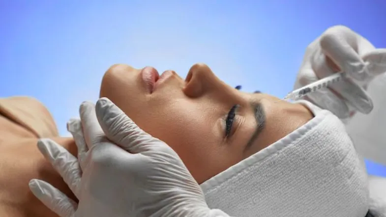 Estética avançada pode aplicar Botox? Saiba quem está autorizado no Brasil 6 Aplicação de toxina botulínica na testa de uma paciente por profissional com luvas, representando prática segura na estética injetável.