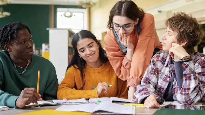 ProUni 2025: guia completo com regras, inscrições, requisitos e como garantir sua bolsa 7 Quatro estudantes fazem trabalho em grupo em ambiente de biblioteca, simbolizando colaboração e preparação acadêmica.