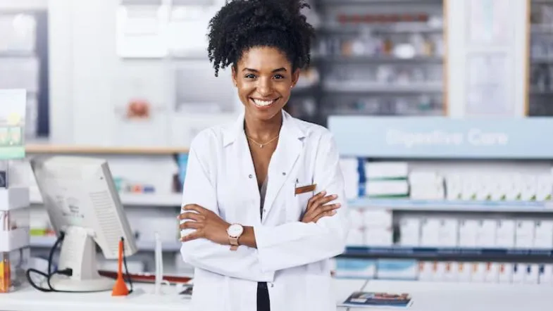 Pós-Graduação em Farmácia Clínica e Atenção Farmacêutica: transforme sua prática profissional 7 Farmacêutica sorridente em ambiente de dispensação, representando o sucesso do profissional especializado com a Pós-Graduação em Farmácia Clínica.