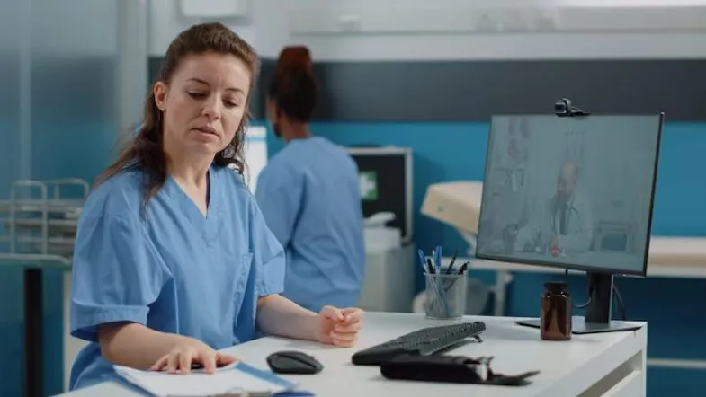 Auditoria em Serviços de Saúde: alavanque sua carreira 7 Enfermeira revisando prontuário médico enquanto participa de videoconferência com profissional da saúde.