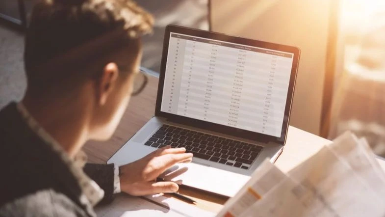 Ciências Contábeis: a profissão que conecta números e propósito 7 Profissional de Ciências Contábeis analisando planilhas financeiras em notebook, com foco em dados e tomada de decisão estratégica.