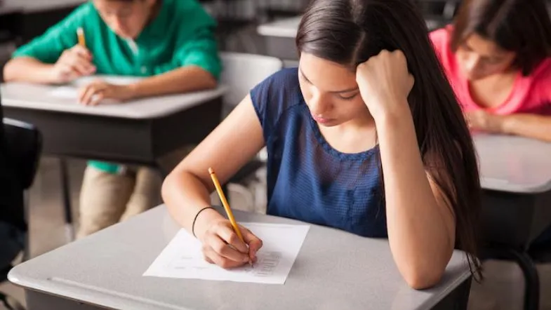 ProUni 2025: guia completo com regras, inscrições, requisitos e como garantir sua bolsa 8 Estudantes sentados em carteiras individuais realizam uma prova, simbolizando exame vestibular ou avaliação do Enem.
