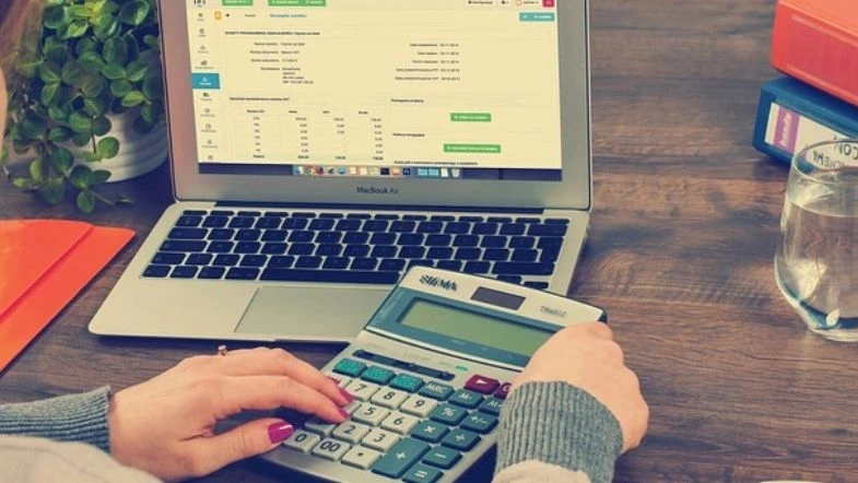 Ciências Contábeis: a profissão que conecta números e propósito 8 Pessoa realizando cálculos financeiros com calculadora e planilha digital em notebook, representando a rotina na área de Ciências Contábeis.