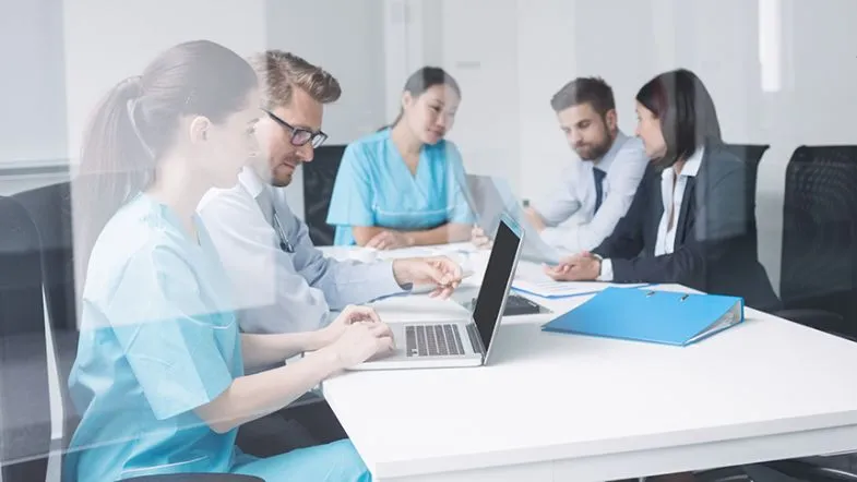 Gestão Hospitalar: transforme seu futuro na saúde e se destaque 7 Grupo de profissionais da saúde e gestão reunidos em sala para planejamento hospitalar.