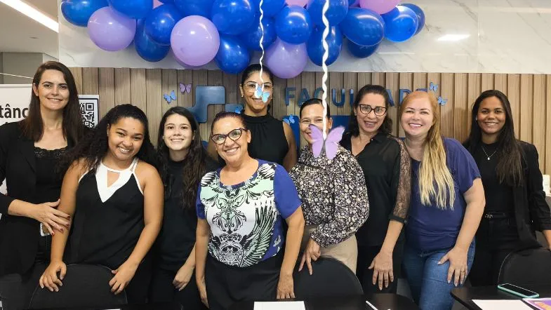 Faculdade ITH conquista nota máxima do MEC no curso de Gestão Hospitalar 7 Alunos da Gestão Hospitalar reunidos em evento comemorativo com decoração azul e roxa celebrando conquistas institucionais.