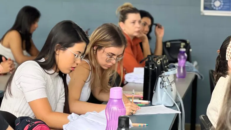 Graduação em Recursos Humanos: guia completo para impulsionar resultados 8 Alunas concentradas em sala de aula, escrevendo em cadernos durante atividade acadêmica.