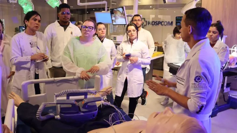 Urgência e Emergência na prática: alunos da pós ITH vivem imersão no centro Hospcom 8 Professor da Faculdade ITH conduz explicação prática sobre suporte avançado de vida para alunos, em sala de simulação hospitalar com equipamentos reais.