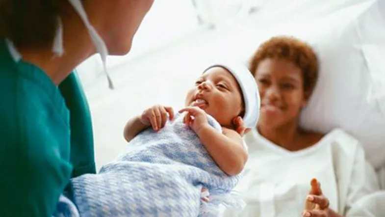 Atuação da enfermeira obstetra no parto humanizado: o que você precisa saber 6 Profissional da saúde entregando um bebê nos braços da mãe logo após o parto, ambos sorrindo.
