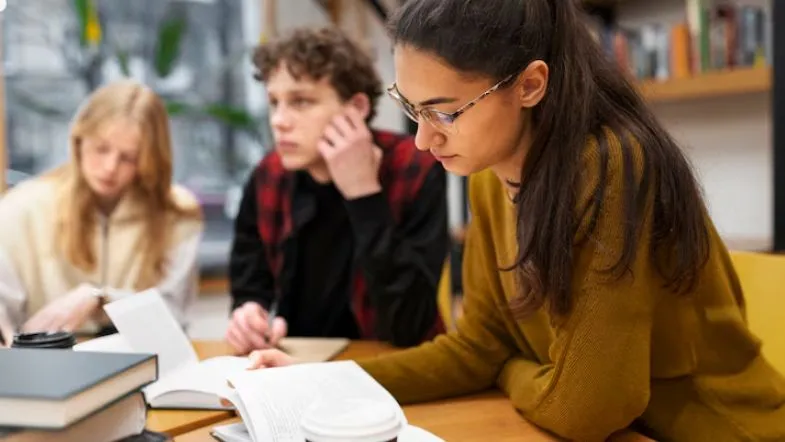 Como se preparar para o ENEM 2025 e conquistar sua vaga na faculdade 6 Jovem concentrada estudando em uma biblioteca estudando para o ENEM 2025.