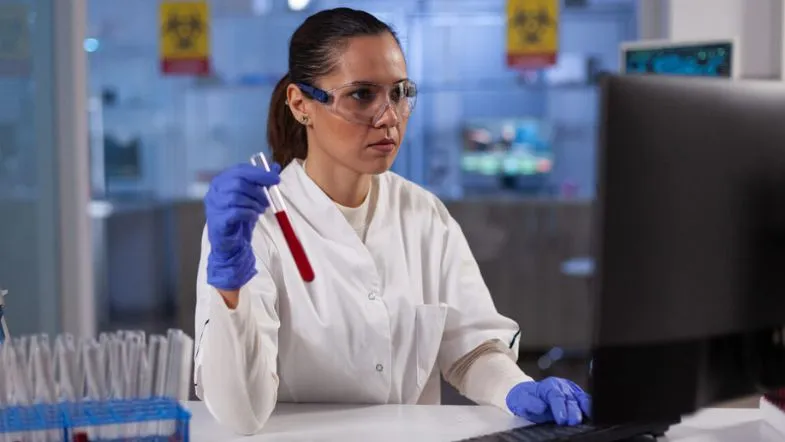 Biomedicina x Medicina: entenda as diferenças e descubra qual escolher 6 Biomédica analisando amostra de sangue em laboratório com uso de computador.
Carreira em Biomedicina, análise clínica, diagnóstico laboratorial, curso de Biomedicina.