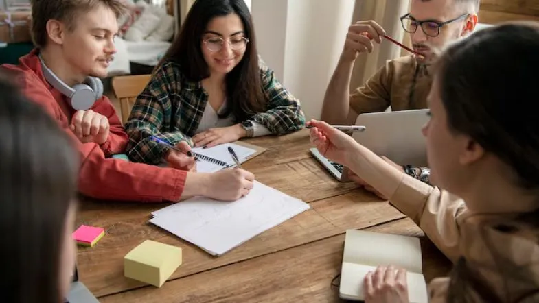 Como se preparar para o ENEM 2025 e conquistar sua vaga na faculdade 7 Grupo de estudantes fazendo plano de estudos em mesa de madeira.