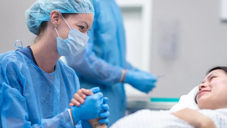 Atuação da enfermeira obstetra no parto humanizado: o que você precisa saber 8 Enfermeira dando apoio emocional e segurando a mão de uma gestante durante o trabalho de parto.