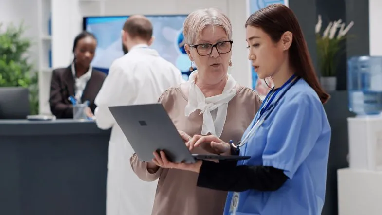 Gestão em Saúde Pública: o que é, como funciona e por que escolher a Faculdade ITH 8 Enfermeira com uniforme azul trocando informações com apoio de tecnologia.