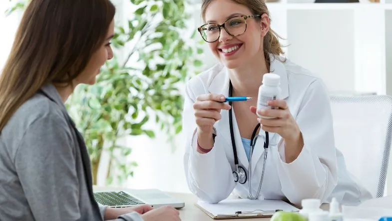 Nutricionista apresenta suplemento em cápsulas durante consulta com paciente em ambiente clínico.