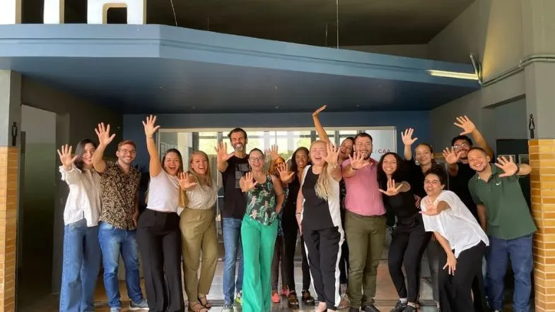 ITH 10 anos: da inovação à liderança no ensino superior brasileiro 9 Equipe da Faculdade ITH comemorando o conceito 5 no MEC da instituição com as mãos levantadas em frente à sede