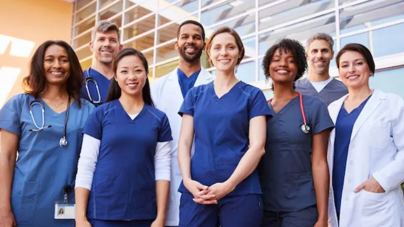 Quais áreas de pós-graduação em Enfermagem estão em alta? Confira as mais requisitadas 9 Dois enfermeiros usando máscaras e toucas cirúrgicas analisando juntos um prontuário, em ambiente clínico, mostrando trabalho em equipe e atenção ao paciente, representando a satisfação profissional daqueles que fazem pós-graduação em enfermagem têm.