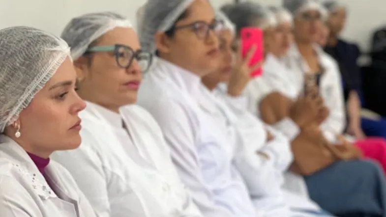 Educação de verdade: como a Faculdade ITH se prepara para os próximos 10 anos 9 Grupo de estudantes em laboratório da Faculdade ITH, usando jalecos e toucas de proteção, atentos a uma explicação ou demonstração prática.