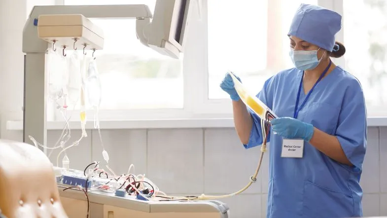 Especialização Técnica em Urgência e Emergência: vale a pena investir nesse curso? 7 Profissional de enfermagem analisando bolsa de sangue em ambiente hospitalar, treinamento prático do curso de especialização em urgência e emergência.