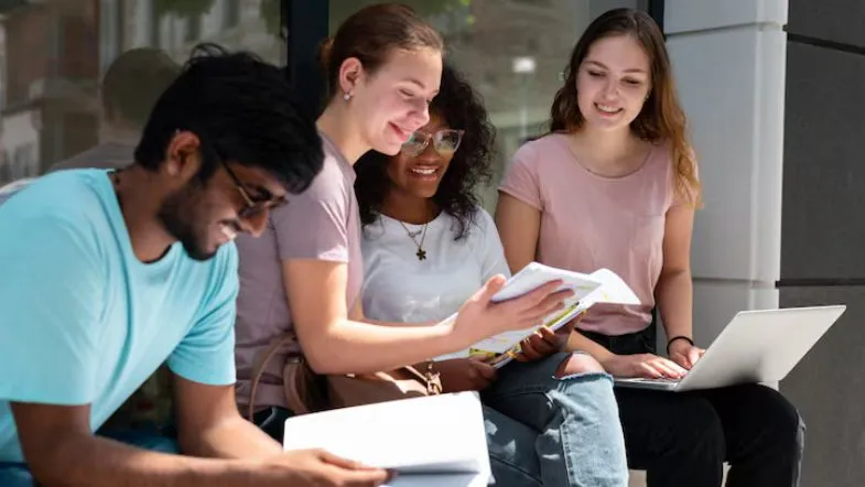 Grupo de jovens estudantes sentados ao ar livre, estudando para o ENEM.
