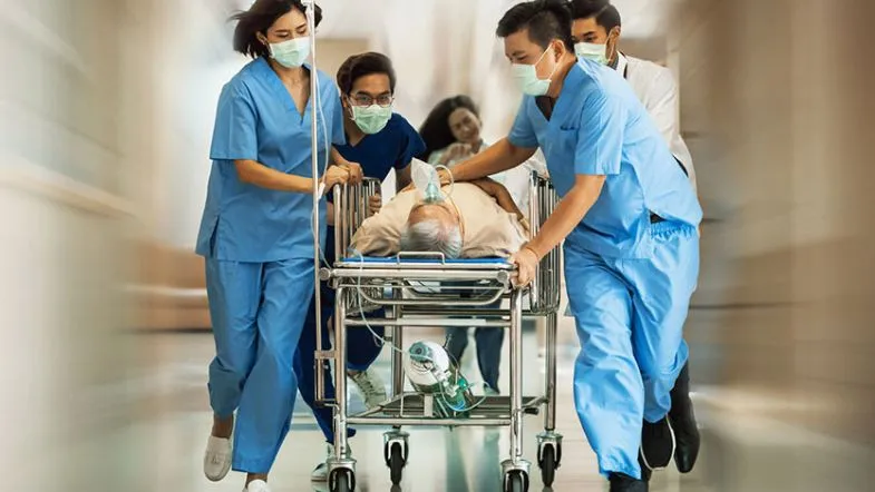 Especialização Técnica em Urgência e Emergência: vale a pena investir nesse curso? 9 Equipe de enfermagem transportando paciente crítico em maca durante situação de emergência hospitalar, foco da especialização técnica em urgência e emergência.