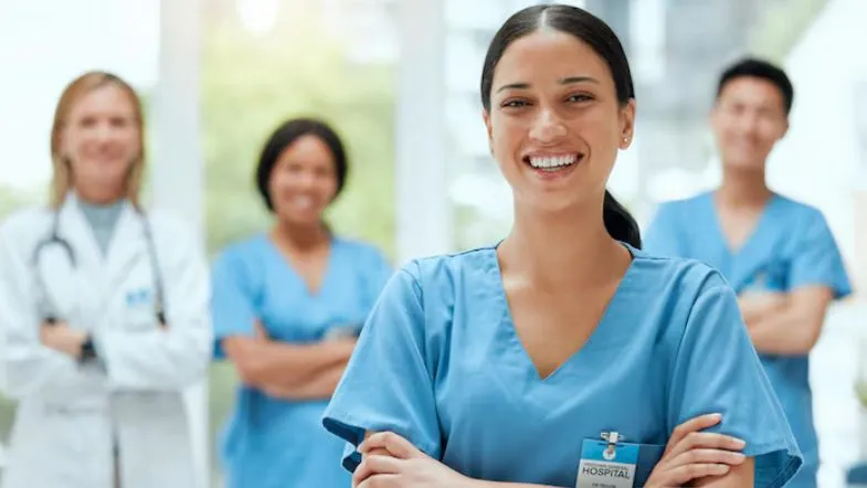 Equipe multiprofissional de saúde sorridente com foco em enfermeira em primeiro plano, simbolizando crescimento profissional e oportunidades na área hospitalar.