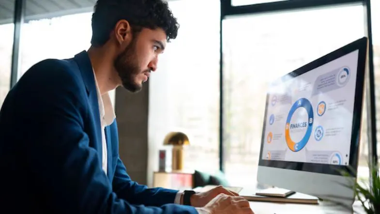 Carreira em Gestão Comercial: salários, áreas de atuação e dicas para se destacar no mercado 11 ovem executivo analisando dados financeiros e indicadores de desempenho no computador.