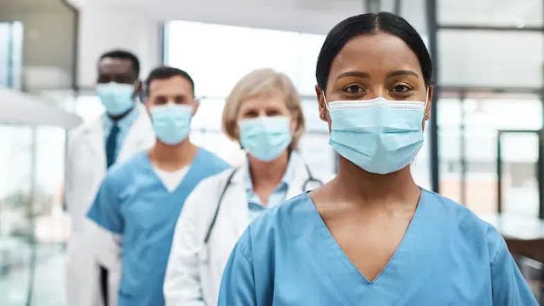 Equipe multidisciplinar de profissionais de saúde usando máscaras em ambiente hospitalar.