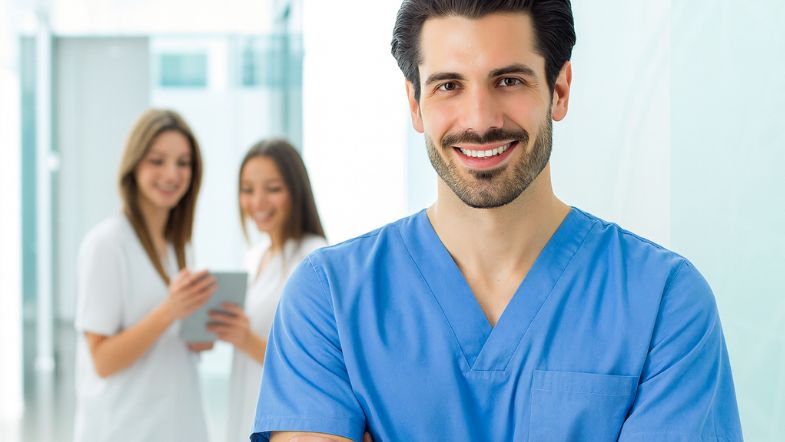 Profissional de saúde com uniforme azul sorrindo, representando confiança e qualidade em serviços hospitalares, aspectos que serão abordados no evento Acreditação 360.