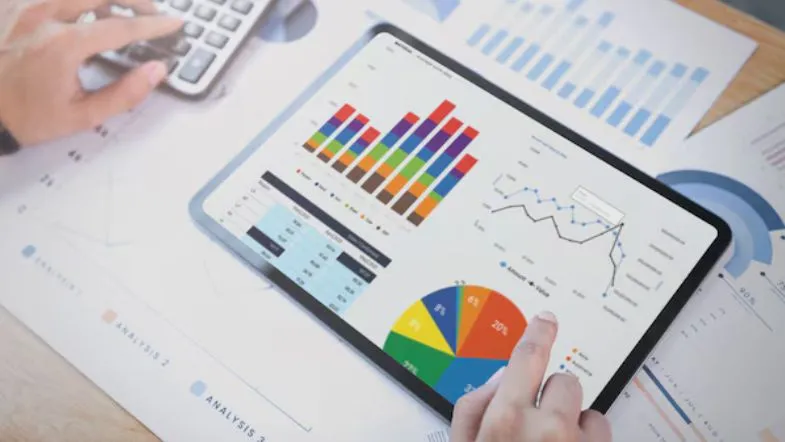 Graduação em Administração: salário, funções, oportunidades e áreas de atuação 11 Análises financeiras em tablet com gráficos e dashboards — rotina de Administração, finanças e BI.