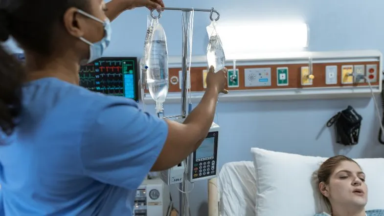Enfermeira ajustando soro intravenoso de paciente em hospital.