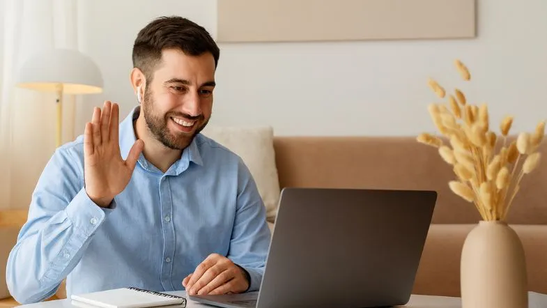 Psicólogo em videoconferência acenando para paciente, representando práticas modernas de atendimento remoto.