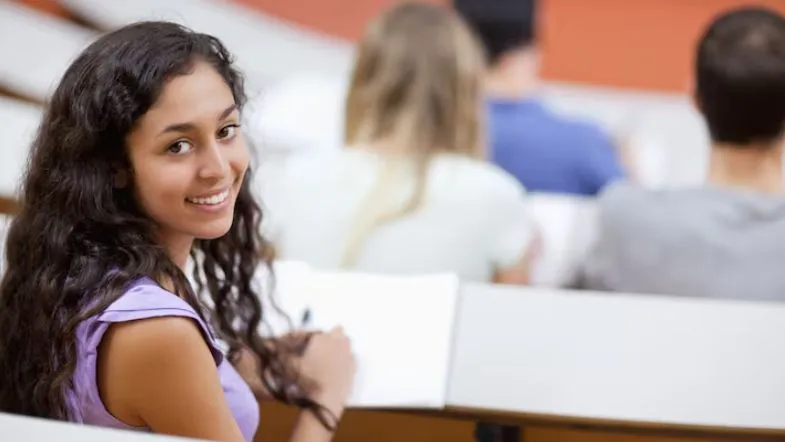 Jovem em sala de aula universitária, sorrindo para a câmera, simbolizando satisfação e confiança na formação escolhida na Faculdade ITH.