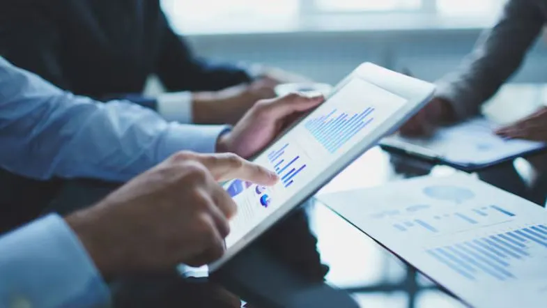 Carreira em Gestão Comercial: salários, áreas de atuação e dicas para se destacar no mercado 15 Profissionais utilizando tablet com gráficos durante reunião corporativa.