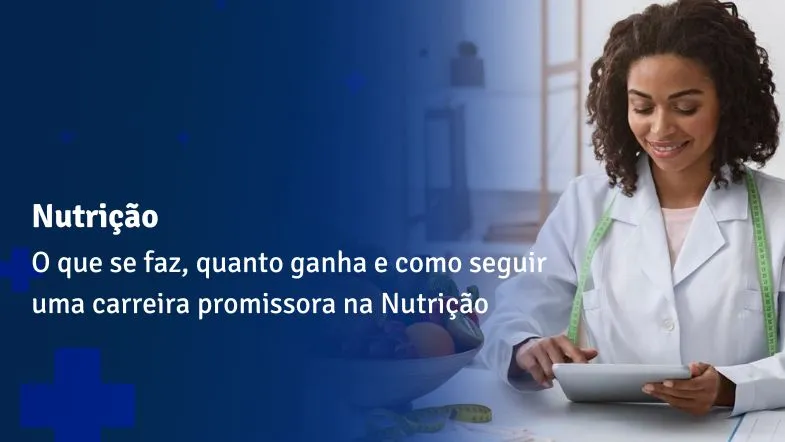 Nutricionista sorridente utilizando tablet em consultório com alimentos ao fundo.