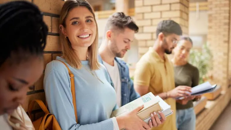 Como escolher a graduação certa: 7 passos para evitar frustrações 6 Grupo de estudantes universitários em corredor de faculdade discutindo sobre qual graduação combina com seu perfil.