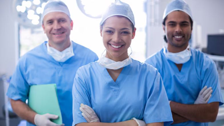 5 erros de liderança que podem desmotivar sua equipe (e como corrigir) 6 Equipe de profissionais da saúde sorrindo, simbolizando liderança positiva e trabalho em equipe.