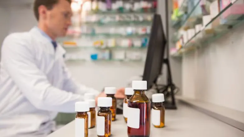 Pós-Graduação em Farmácia: veja qual área combina com o seu perfil profissional 7 Farmacêutico em laboratório analisando frascos de medicamentos, simbolizando a prática e pesquisa clínica nas especializações em Farmácia.