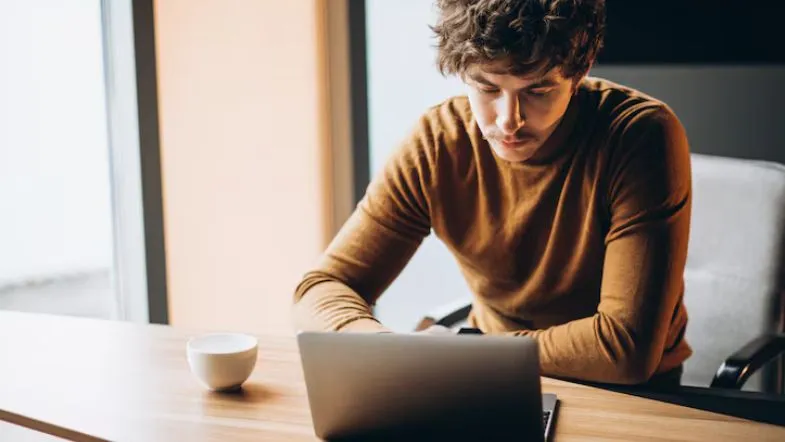 10 pós-graduações com alta empregabilidade em 2025: veja o ranking completo 7 Jovem estudando em casa com notebook, representando ensino a distância de pós-graduação.