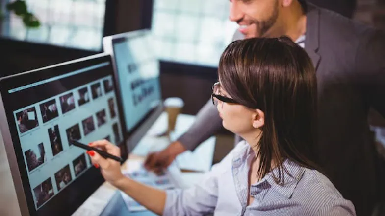Inteligência emocional na liderança: diferencial que transforma profissionais em referência 7 Profissionais colaborando e analisando imagens em tela de computador, representando trabalho estratégico e analítico.