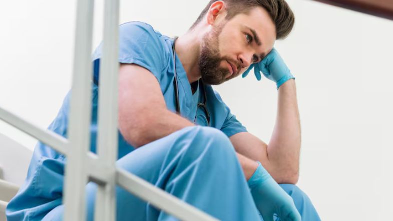 5 erros de liderança que podem desmotivar sua equipe (e como corrigir) 7 Profissional de enfermagem demonstrando cansaço e desmotivação no ambiente de trabalho.