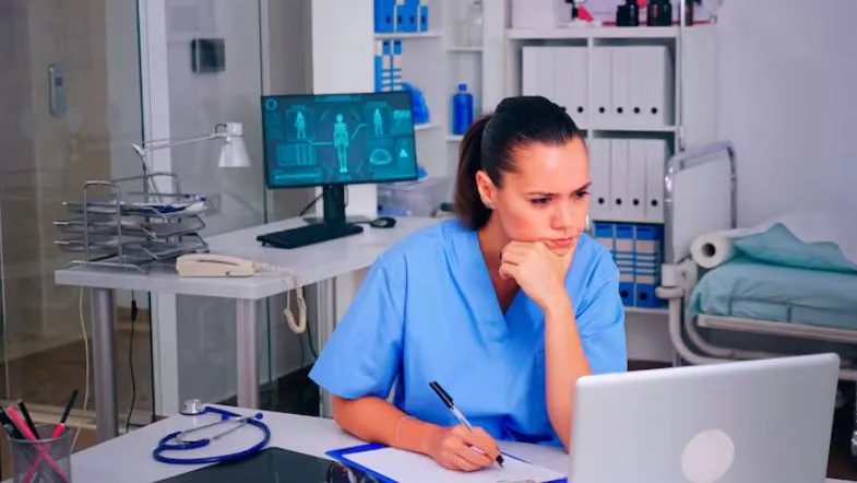 Profissional de saúde estudando em frente ao computador, representando atualização profissional e educação continuada.