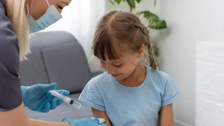 Enfermeira vacinando uma criança durante ação de imunização infantil.