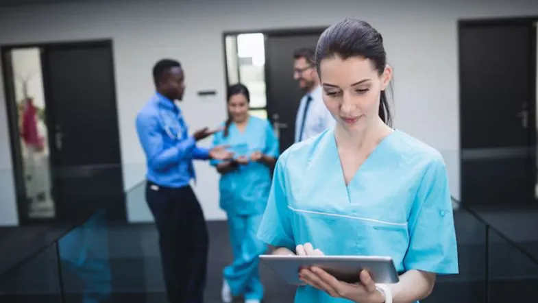 Inteligência emocional na liderança: diferencial que transforma profissionais em referência 8 Enfermeira utilizando tablet em ambiente hospitalar, representando liderança digital e empática na área da saúde.