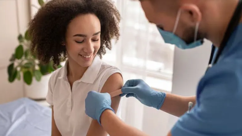 Profissional de saúde colocando curativo no braço de paciente após coleta de sangue, reforçando o cuidado humanizado e a segurança do paciente.