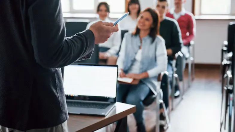 Como escolher a graduação certa: 7 passos para evitar frustrações 8 Professor ministra aula presencial para turma universitária em ambiente moderno e interativo.