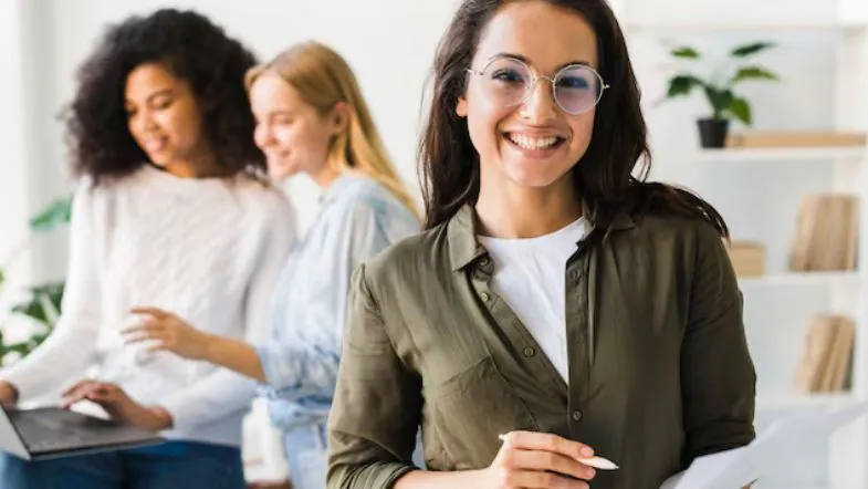 10 pós-graduações com alta empregabilidade em 2025: veja o ranking completo 9 Profissional confiante sorrindo enquanto colegas trabalham em equipe, simbolizando sucesso após realizar uma das pós-graduações da Faculdade ITH.