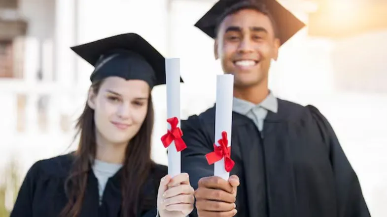 Homem e mulher com becas e diplomas nas mãos, representando graduados da Faculdade ITH em Goiânia.