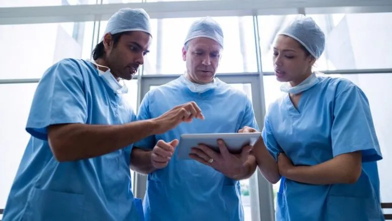 Como a Inteligência Artificial está redefinindo diagnósticos e tratamentos na saúde 13 Equipe médica avaliando dados em tablet durante procedimento hospitalar.